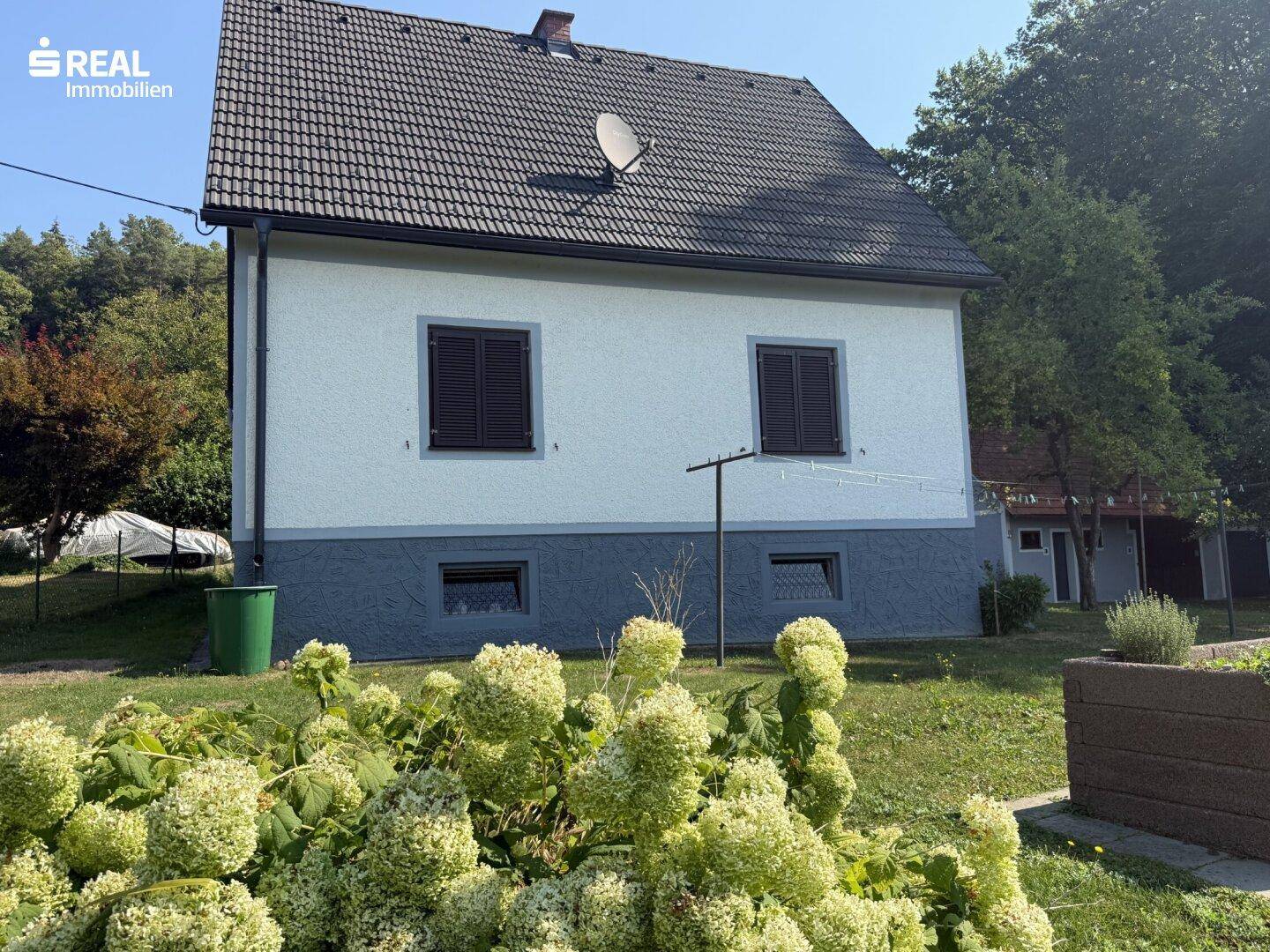 Rückseite des Hauses mit Garten und Blick auf die umliegende grüne Landschaft.