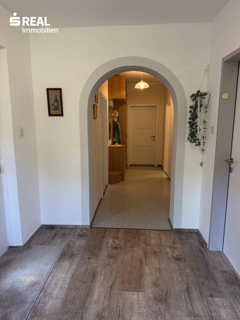 Geräumiger Flur mit Holzboden und einem eleganten Rundbogen, der zu weiteren Räumen führt.