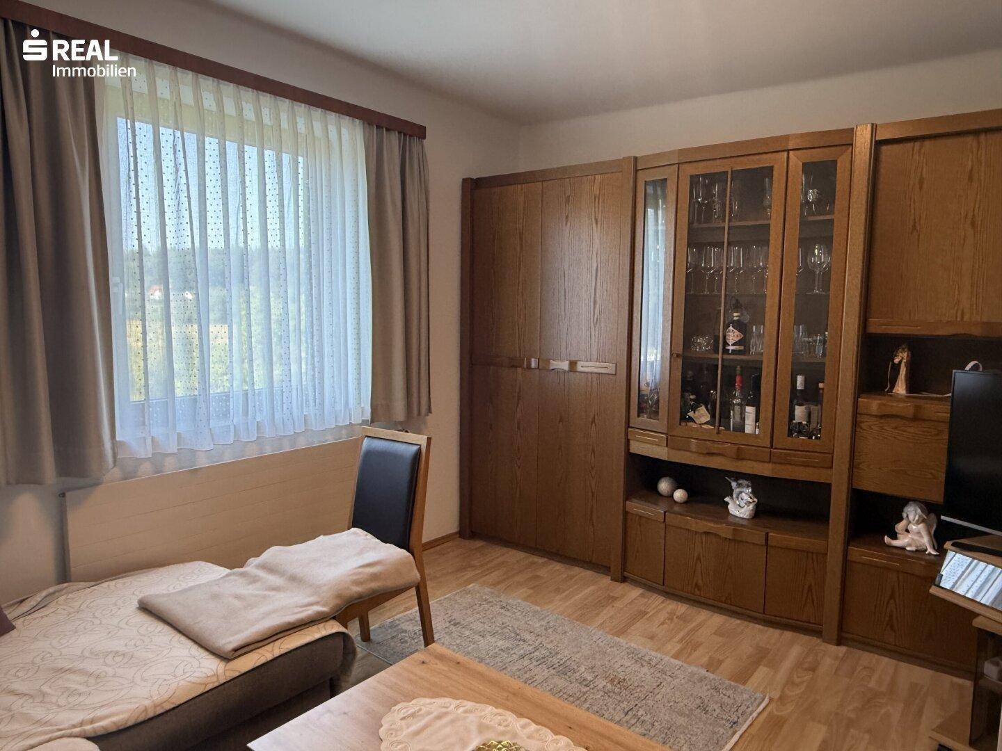 Schlafzimmer mit Holzmöbeln, großem Fenster und Blick auf die Landschaft.