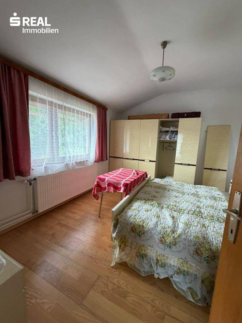 Gemütliches Schlafzimmer mit Holzboden, großem Kleiderschrank und Blick ins Grüne.