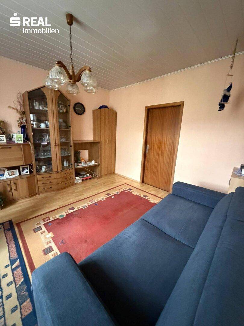 Gemütliches Wohnzimmer mit Sofa, Vitrine und Holzboden, ideal für entspannte Abende.