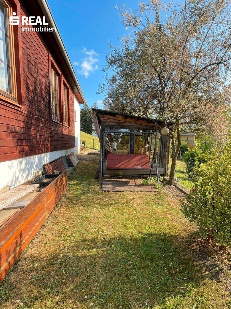 Idyllischer Gartenbereich mit einer Hollywoodschaukel unter einem Baum, ideal zum Entspannen.