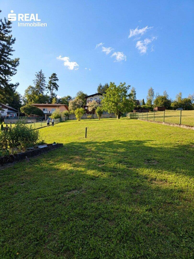 Weitläufige Rasenfläche mit Blick auf die umliegende Hügellandschaft und weitere Häuser.