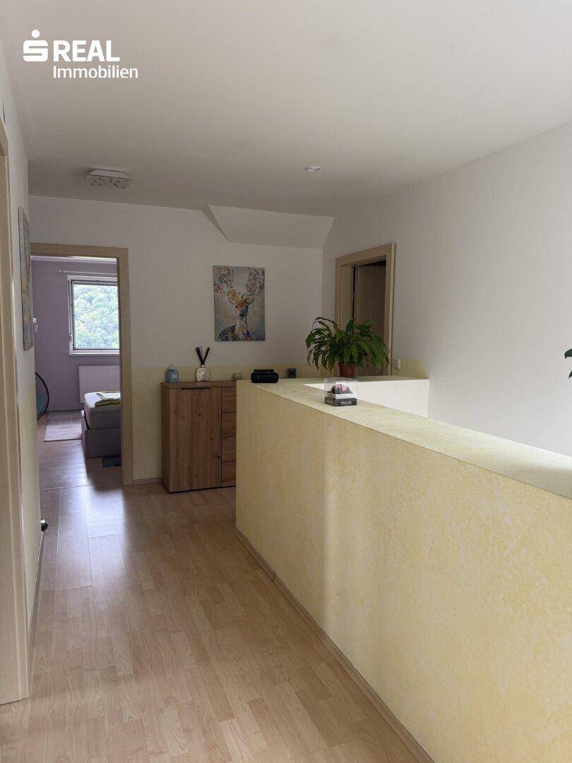 Heller Flur im Obergeschoss mit Holzfußboden und Blick in ein weiteres Zimmer.