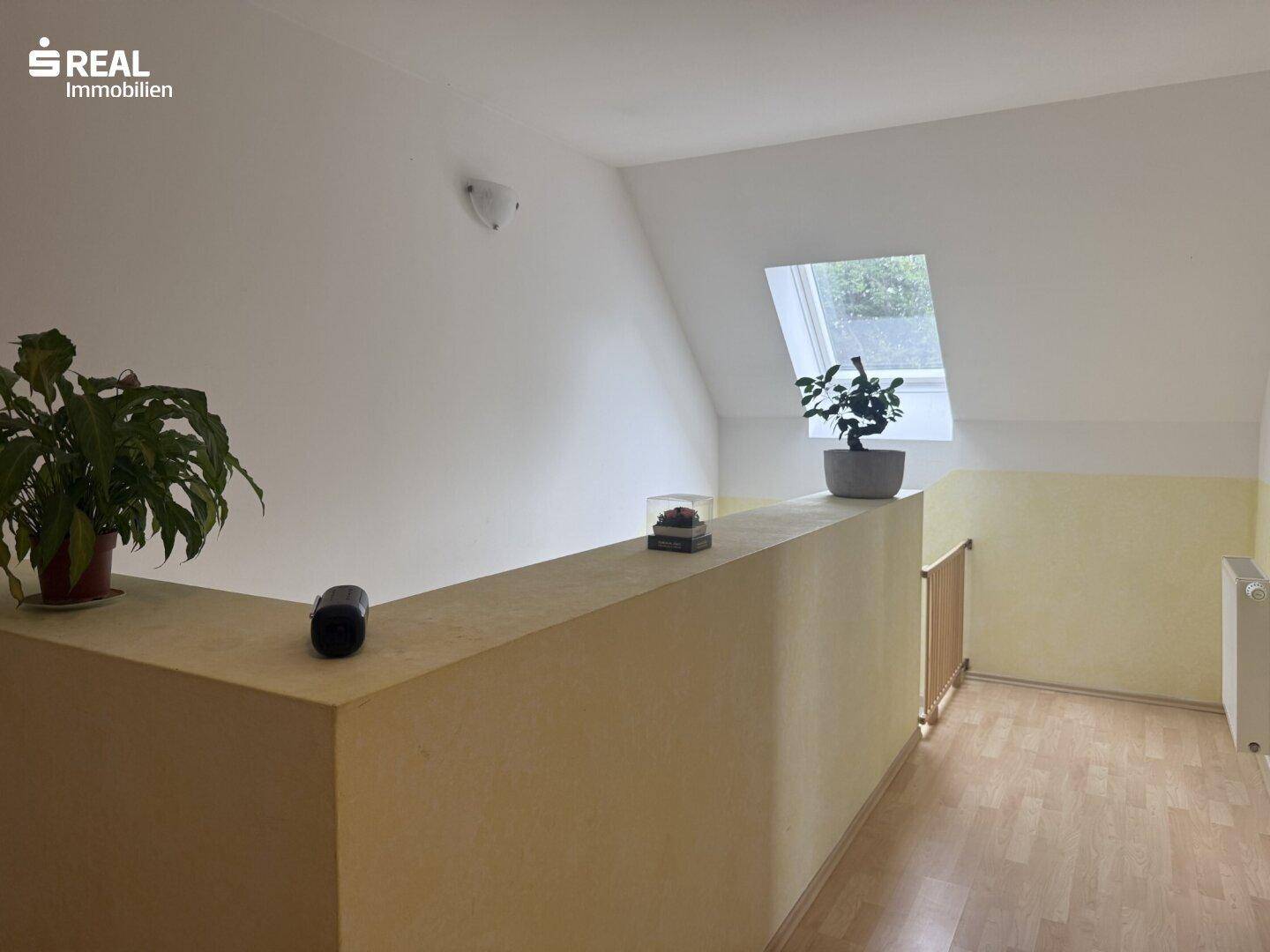 Heller Flur im Obergeschoss mit Dachfenster und Pflanzen.