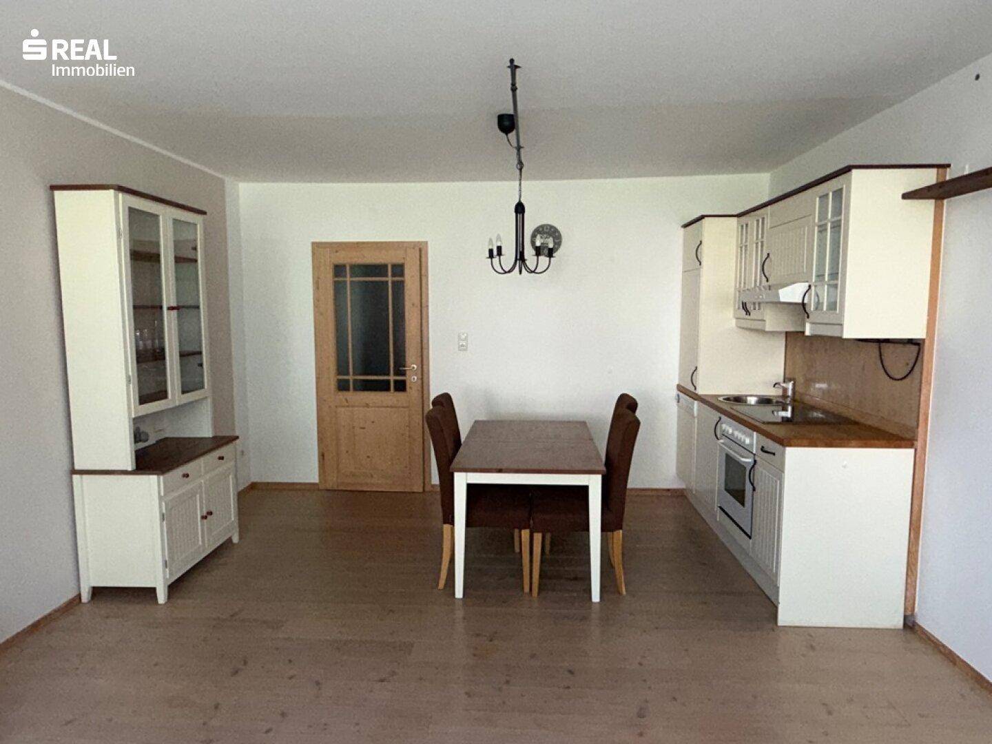 Essbereich mit Holztisch und Stühlen, angrenzend an die Küche und einen Schrank.