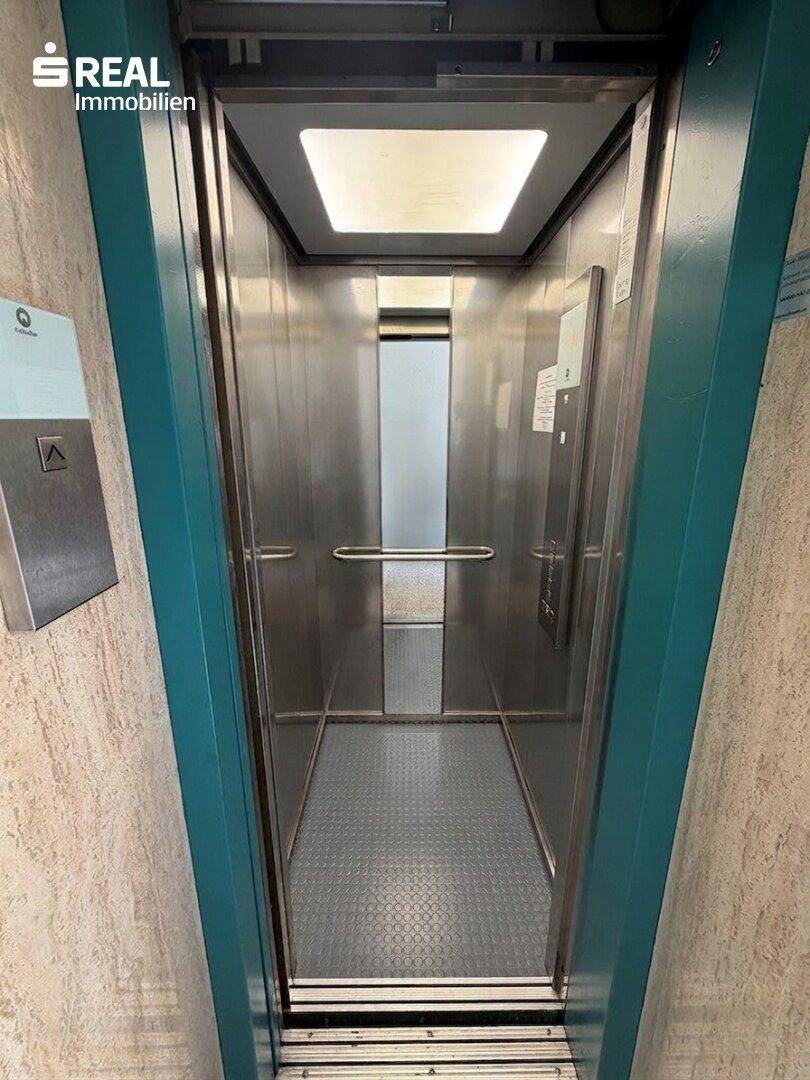 Moderner Aufzug mit Edelstahloberflächen und blauen Akzenten im Inneren des Gebäudes.