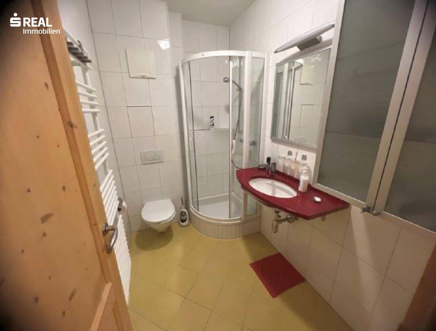 Badezimmer mit Duschkabine, WC, Waschbecken und beheiztem Handtuchhalter.