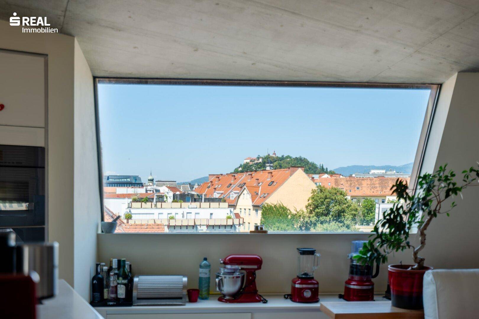 Große Fensterfront mit Panoramablick über die Stadt und die umliegenden Dächer.