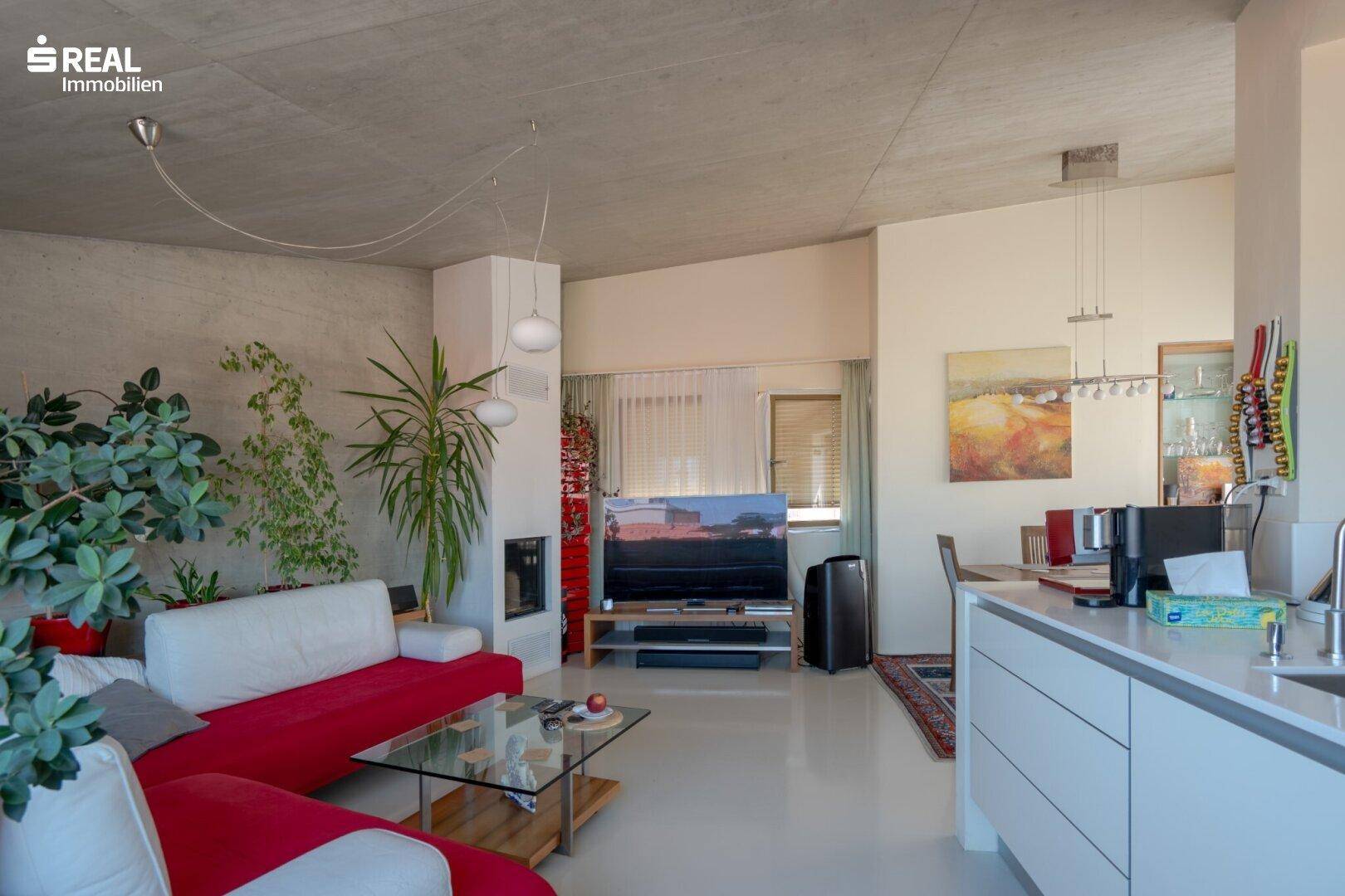 Geräumiges Wohnzimmer mit Kamin, roten Sofas und Blick auf die Stadt.