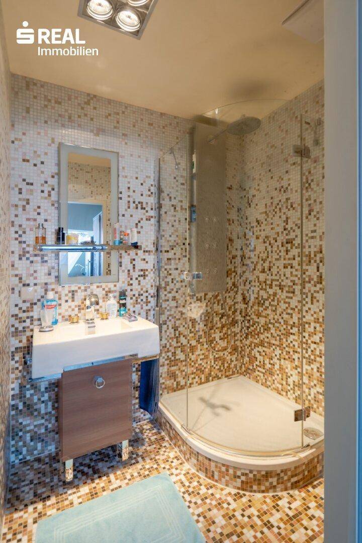Modernes Badezimmer mit Mosaikfliesen, Dusche und Einzelwaschbecken.