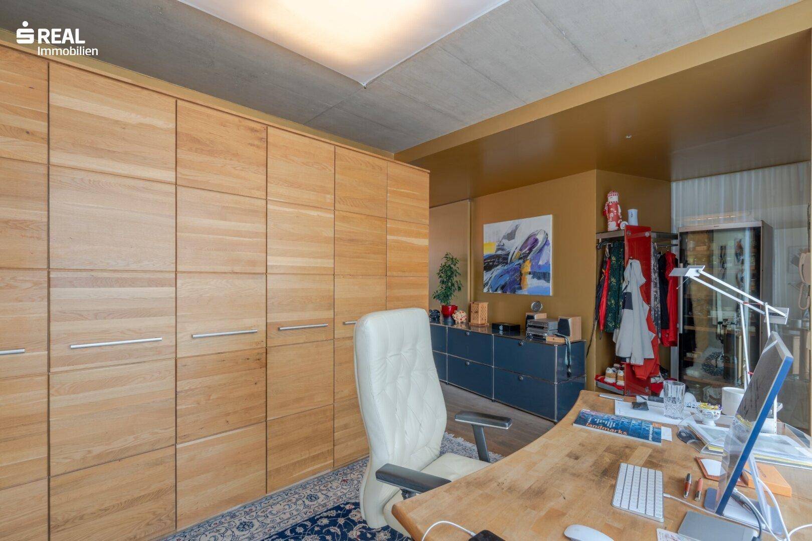 Arbeitsbereich mit Holzschränken, Schreibtisch und Teppichboden.