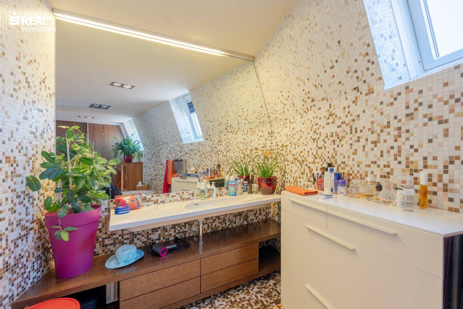 Geräumiges Badezimmer mit Mosaikfliesen, Doppelwaschbecken und Dachfenster.