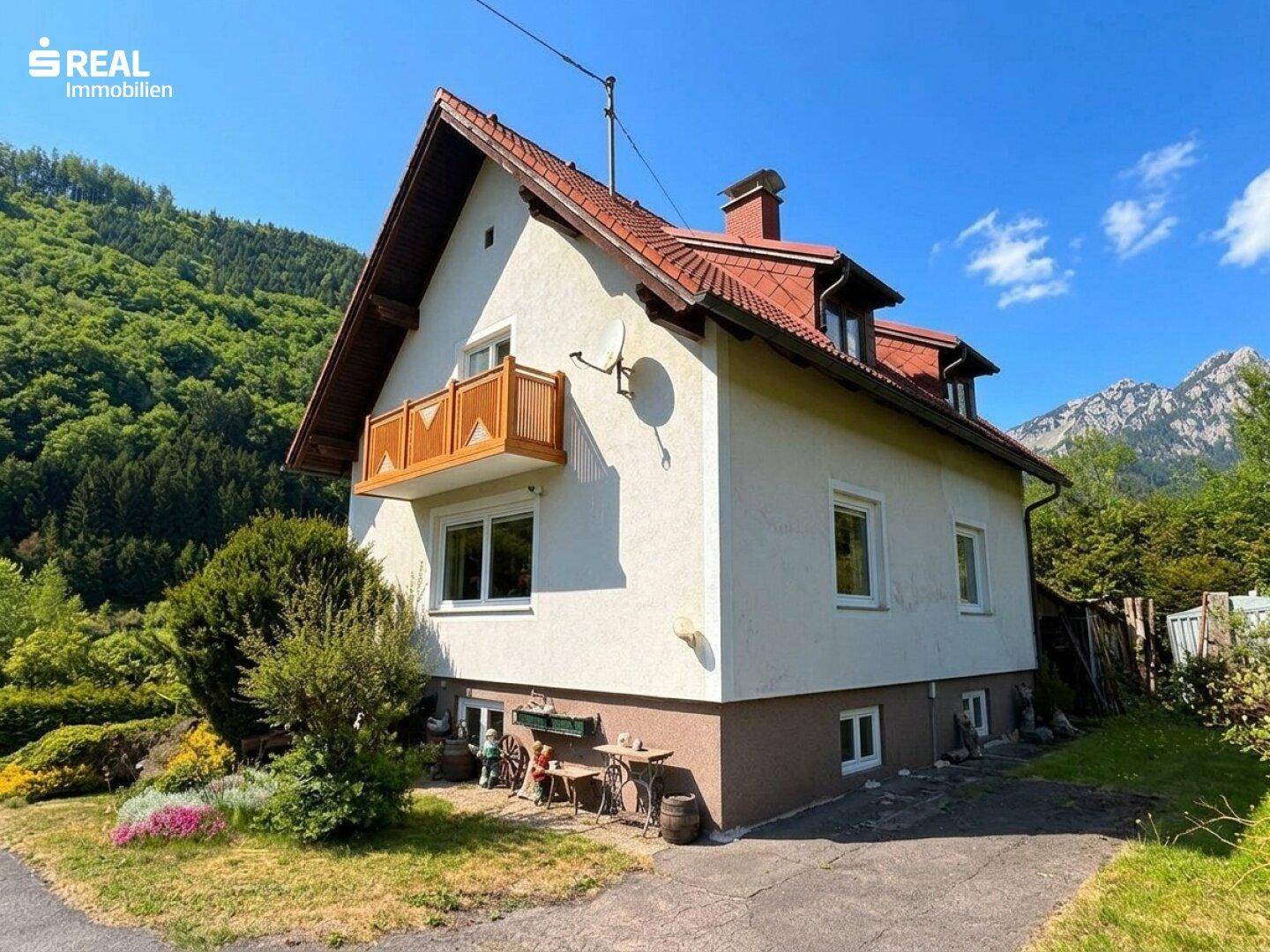 Freistehendes Haus mit Balkon und Garten, eingebettet in eine malerische Berglandschaft.