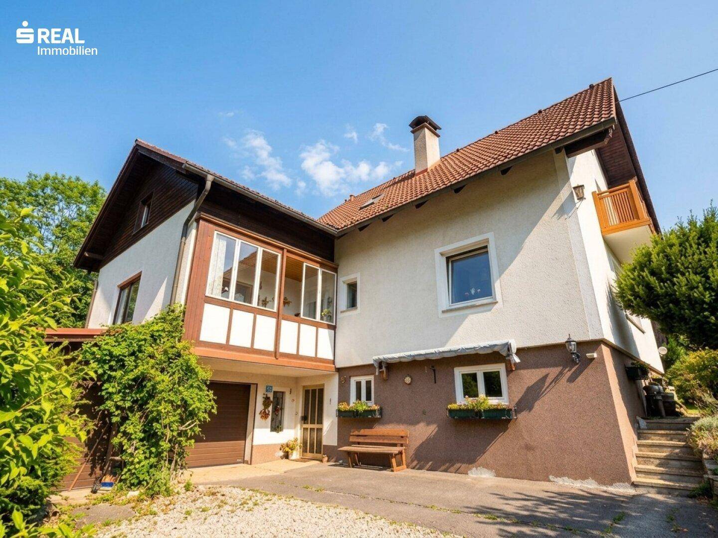 Ansicht des Hauses von der Seite mit Garagenzugang und einem kleinen Sitzbereich im Freien.