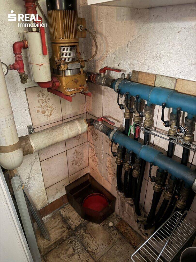 Kellerraum mit Heizungsrohren, Pumpen und technischen Installationen.