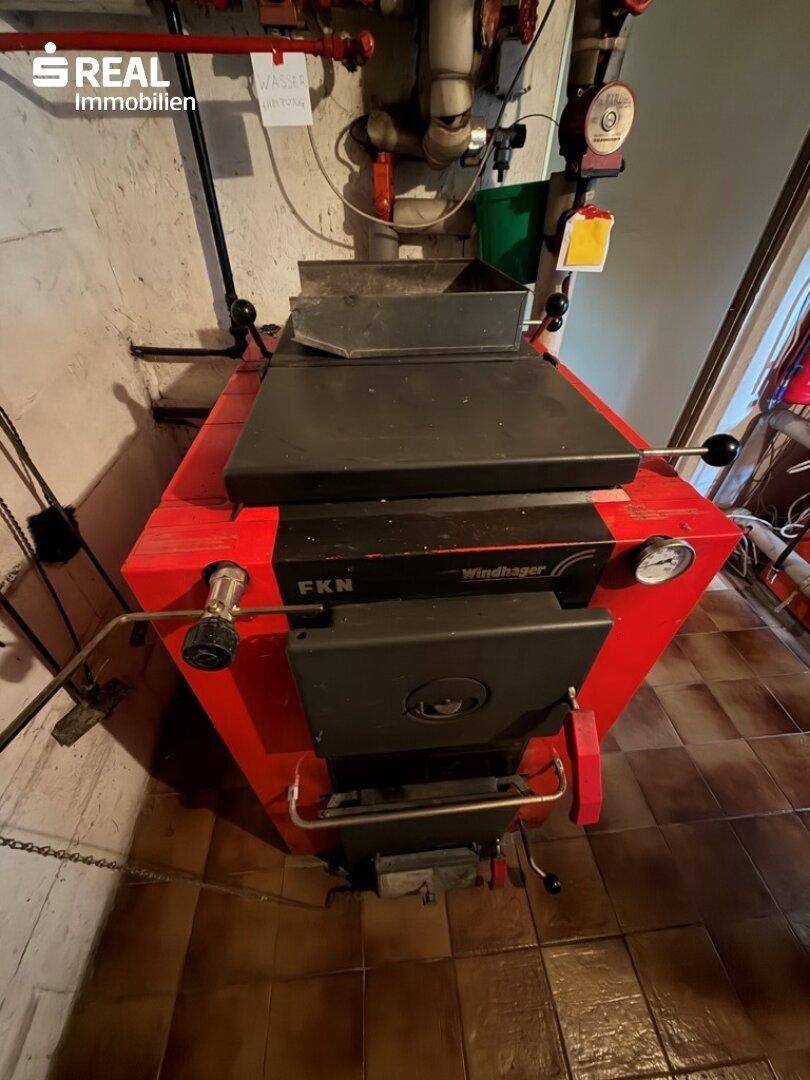 Heizkessel im Keller mit roter Verkleidung und technischen Anschlüssen.