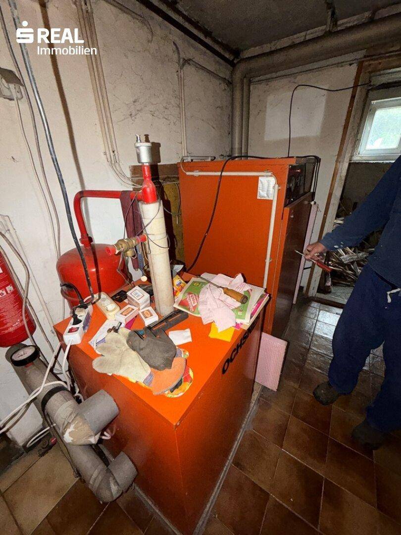 Heizungsraum im Keller mit altem Heizkessel und verschiedenen Geräten.