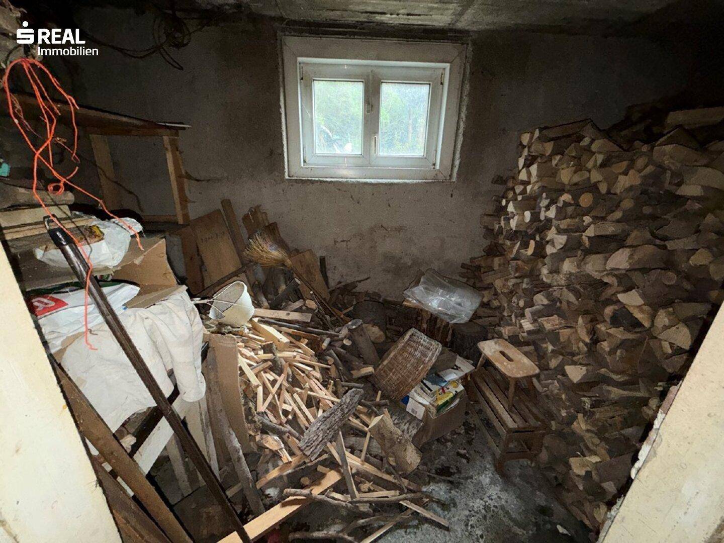 Holzlagerkeller mit gestapeltem Brennholz und kleinem Fenster.