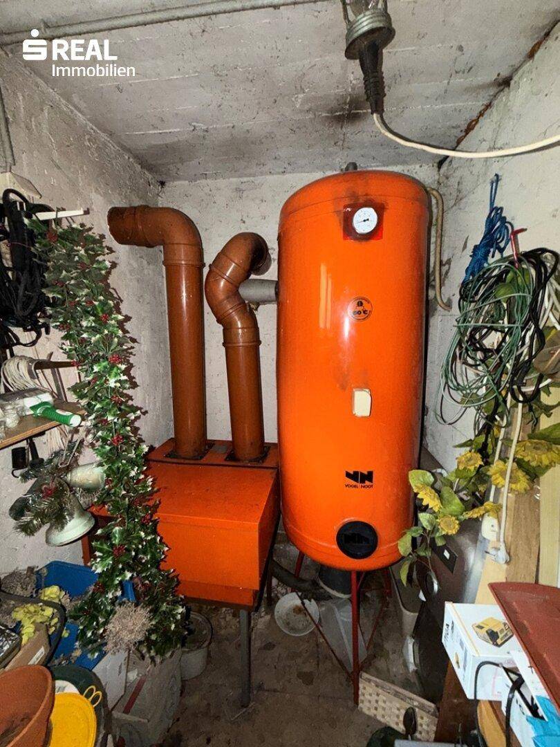 Kellerraum mit Warmwasserspeicher, Rohren und Lagerflächen.