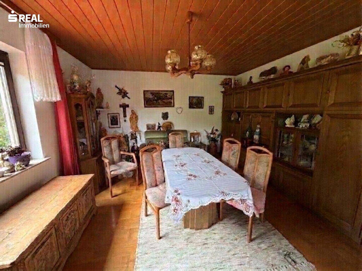 Geräumiges Esszimmer mit großem Holztisch, Stühlen und traditionellen Holzmöbeln.