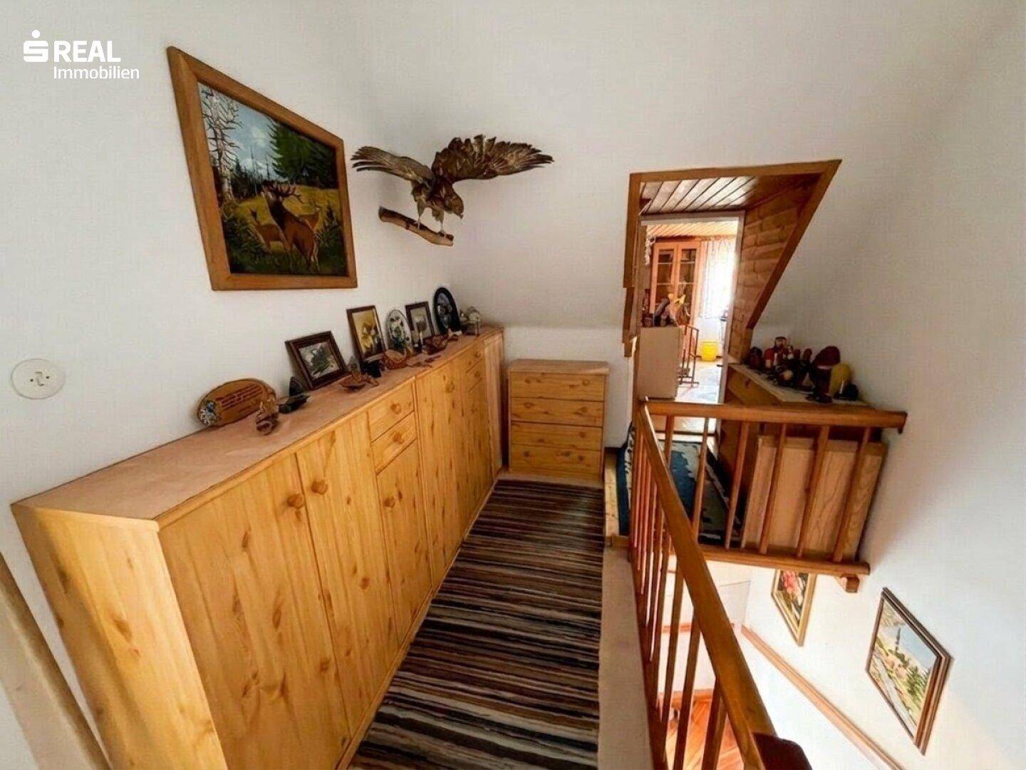 Flur im Obergeschoss mit Holzschränken, Teppichläufer und Blick auf die Treppe.