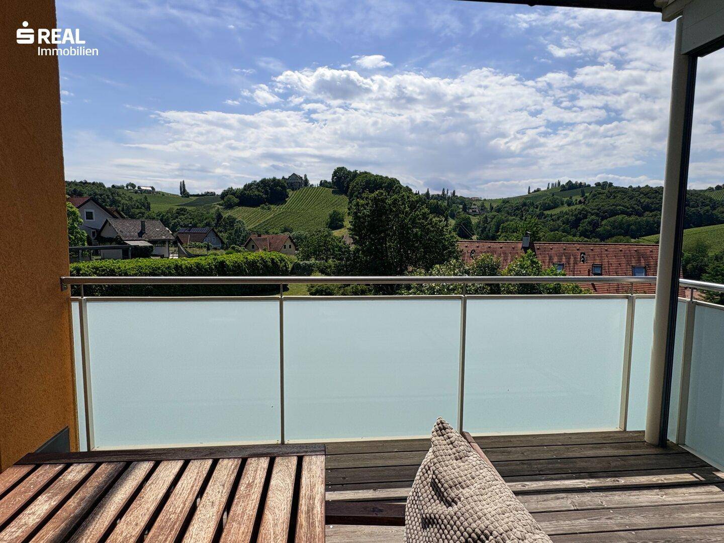 Heller Balkon mit Holzboden und Milchglasbrüstung bietet weite Aussicht auf die Landschaft.