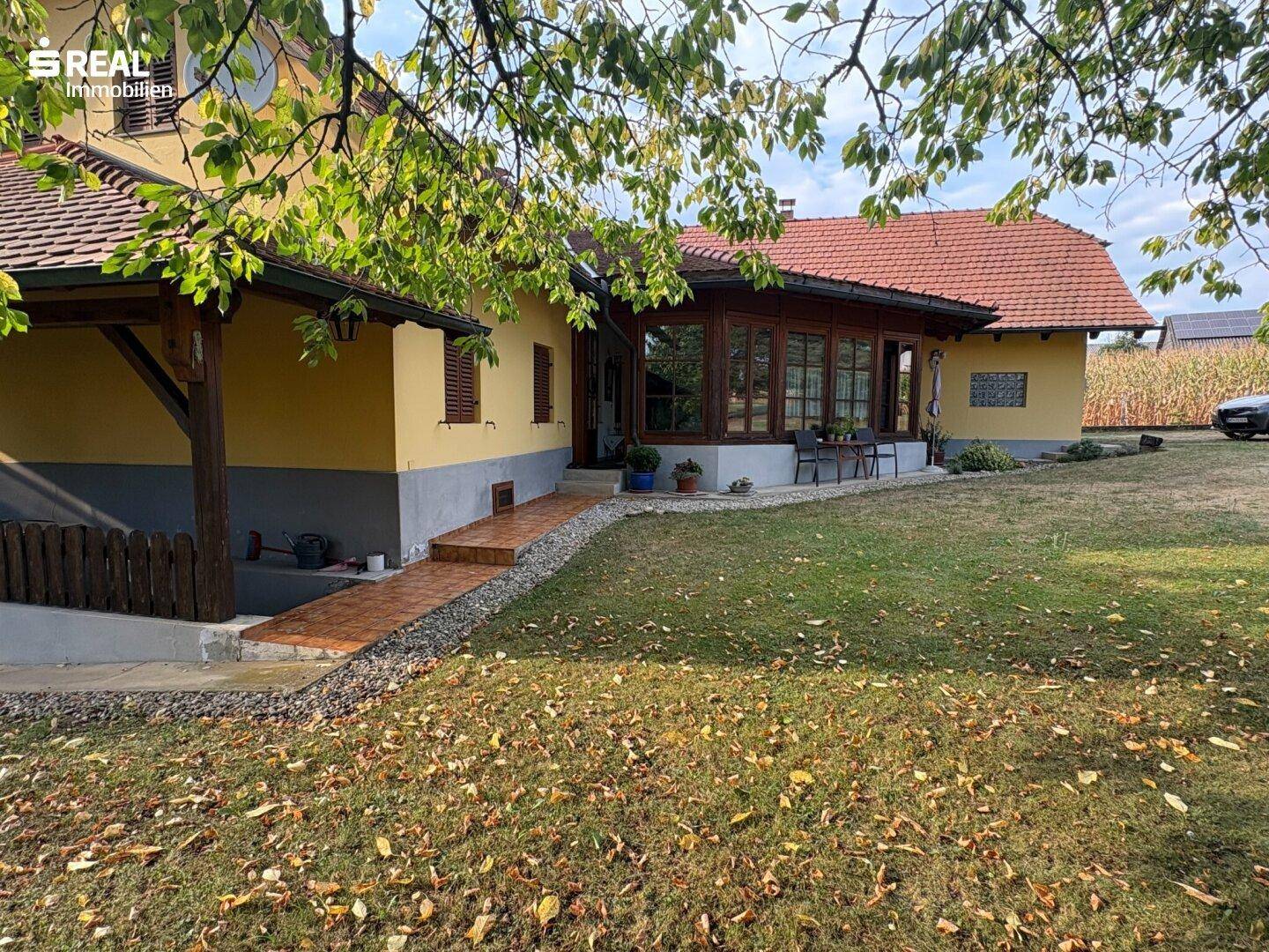 Eingangsbereich des Hauses mit gelber Fassade, rotem Dach und Zugang zum Garten.