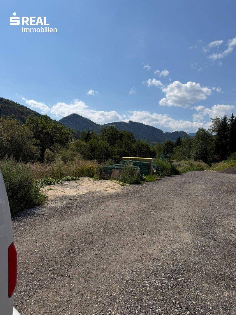 Weitläufiges Grundstück mit Blick auf die grüne Berglandschaft unter blauem Himmel.