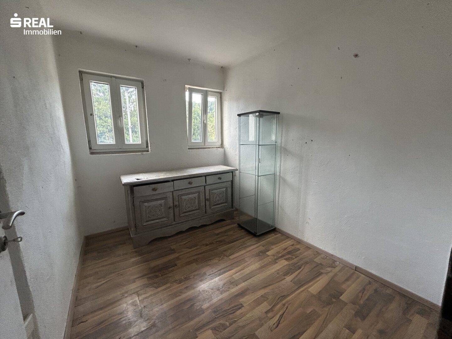 Kleines Zimmer mit Holzboden und einem antiken Holzschrank, ideal als Gästezimmer.