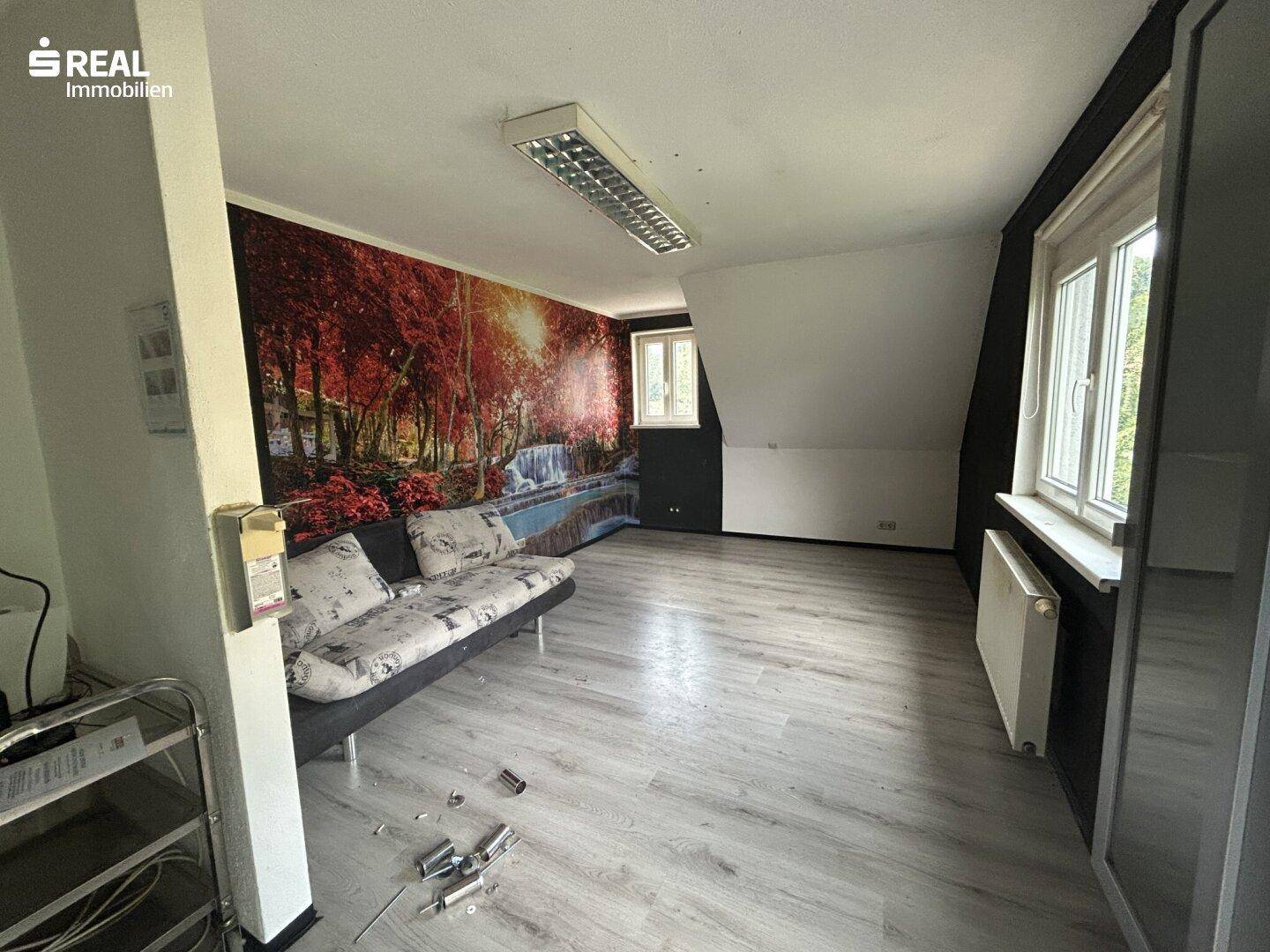 Schlafzimmer mit Laminatboden, schrägen Wänden und einer farbenfrohen Fototapete.