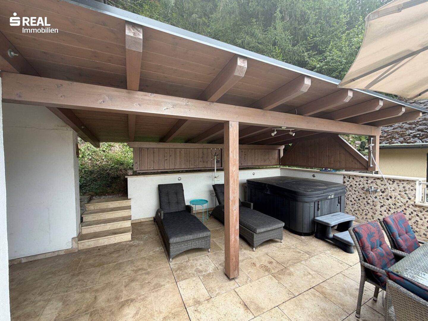 Überdachte Terrasse mit Whirlpool und Liegeflächen, ideal zum Entspannen im Freien.