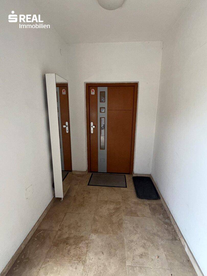 Eingangsbereich mit zwei Türen und hellen Fliesen, bietet Zugang zu den Wohnräumen.