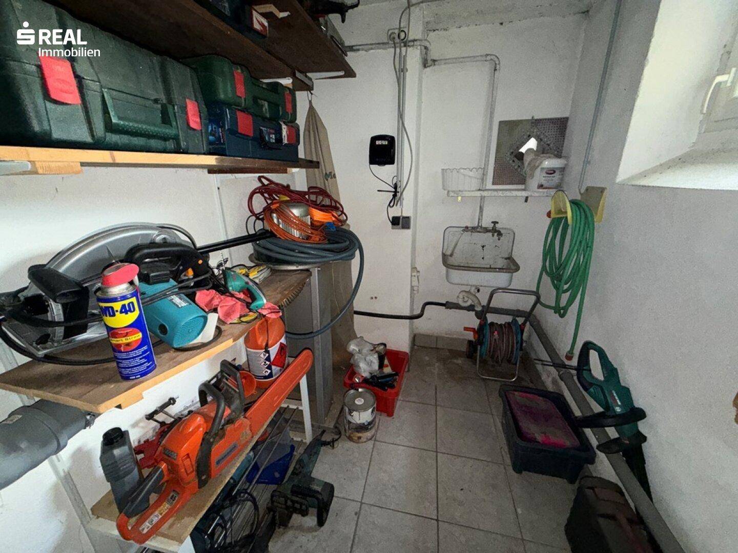 Kellerraum mit verschiedenen Gartengeräten, Werkzeugen und einem Waschbecken.