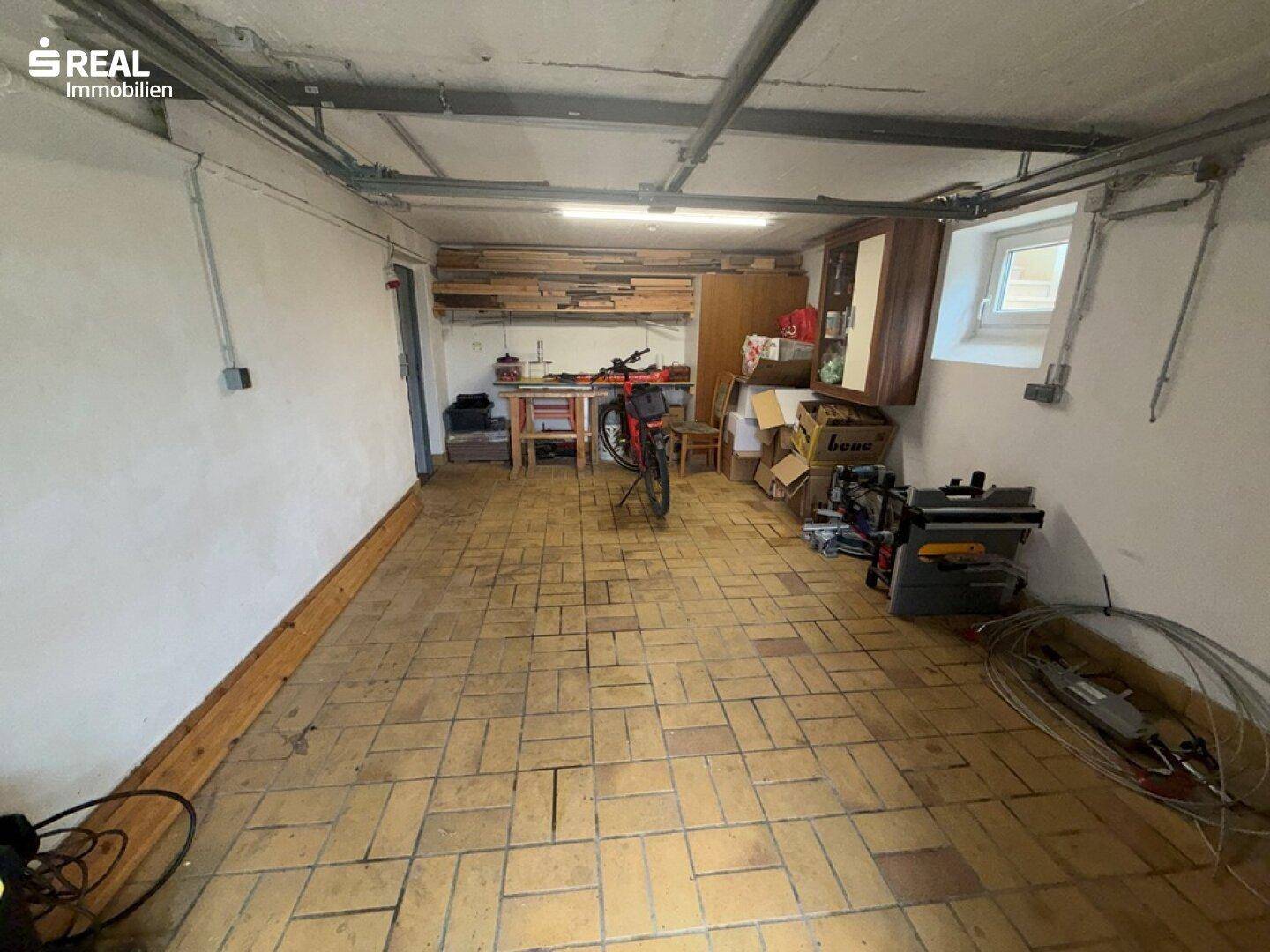 Großer Kellerraum mit Fliesenboden, der als Garage oder Lagerfläche genutzt werden kann.