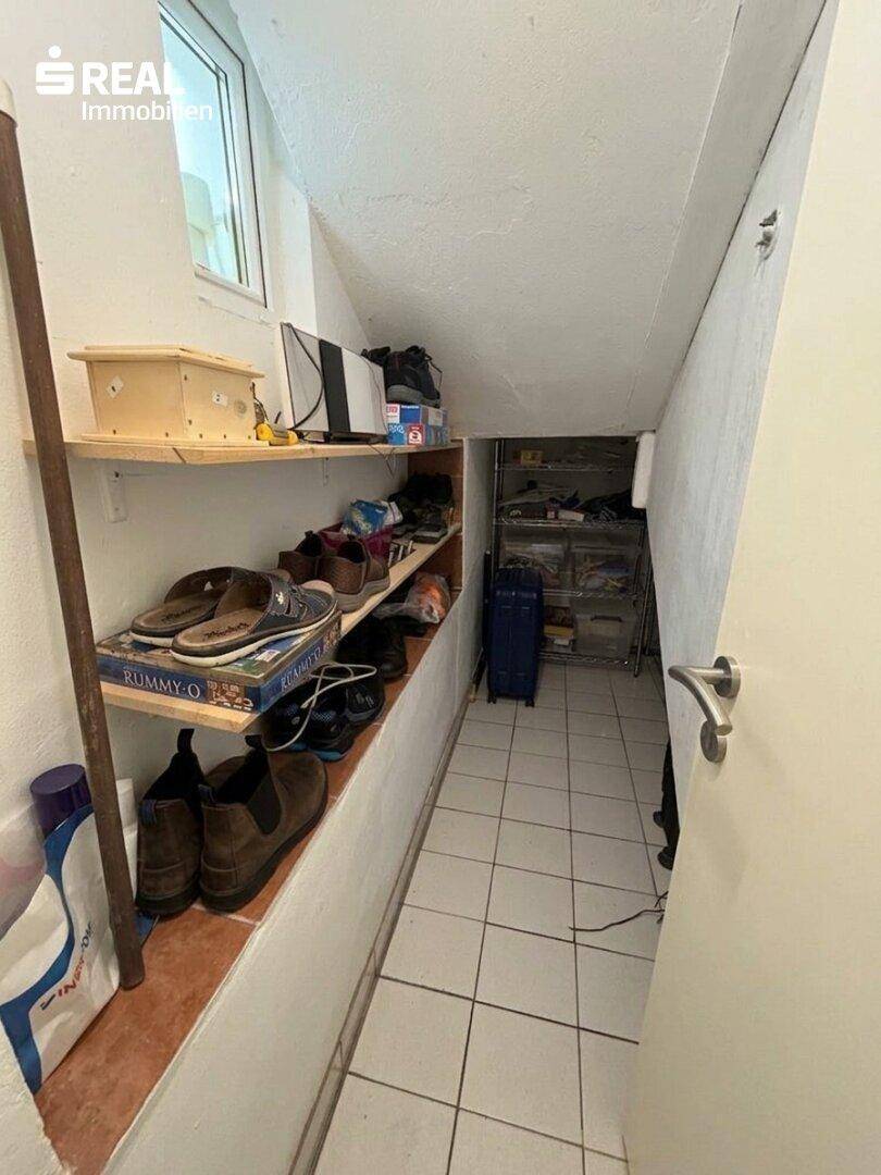 Stauraum unter der Treppe mit Regalen für Schuhe und diverse Gegenstände.