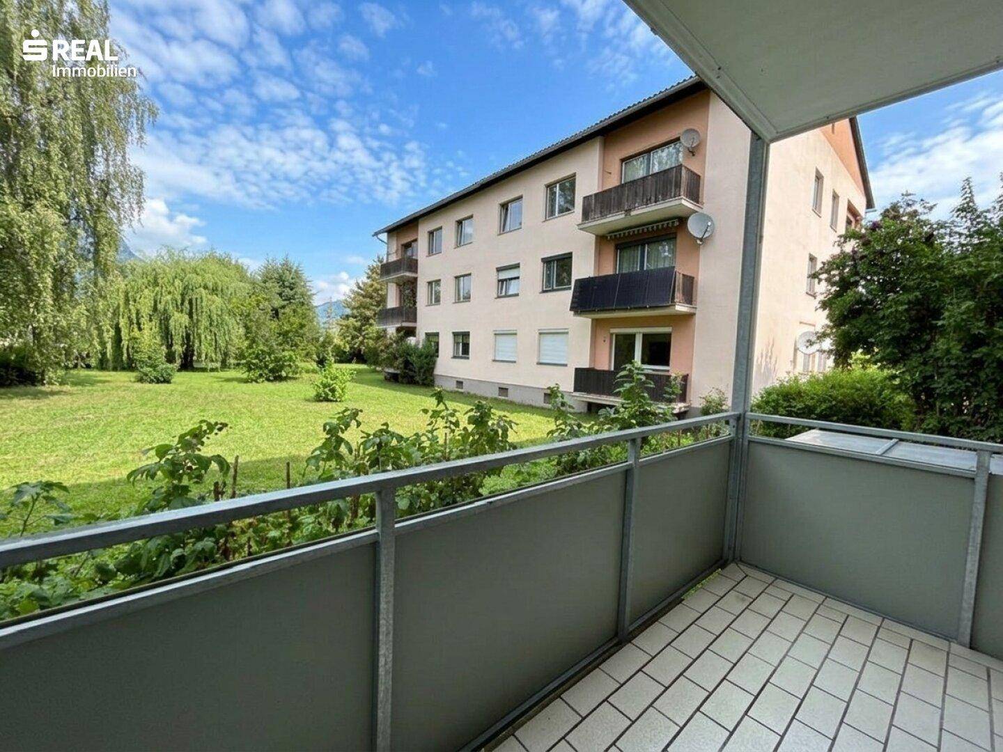 Geräumiger Balkon mit Blick auf die grüne Gartenanlage und das Wohngebäude.