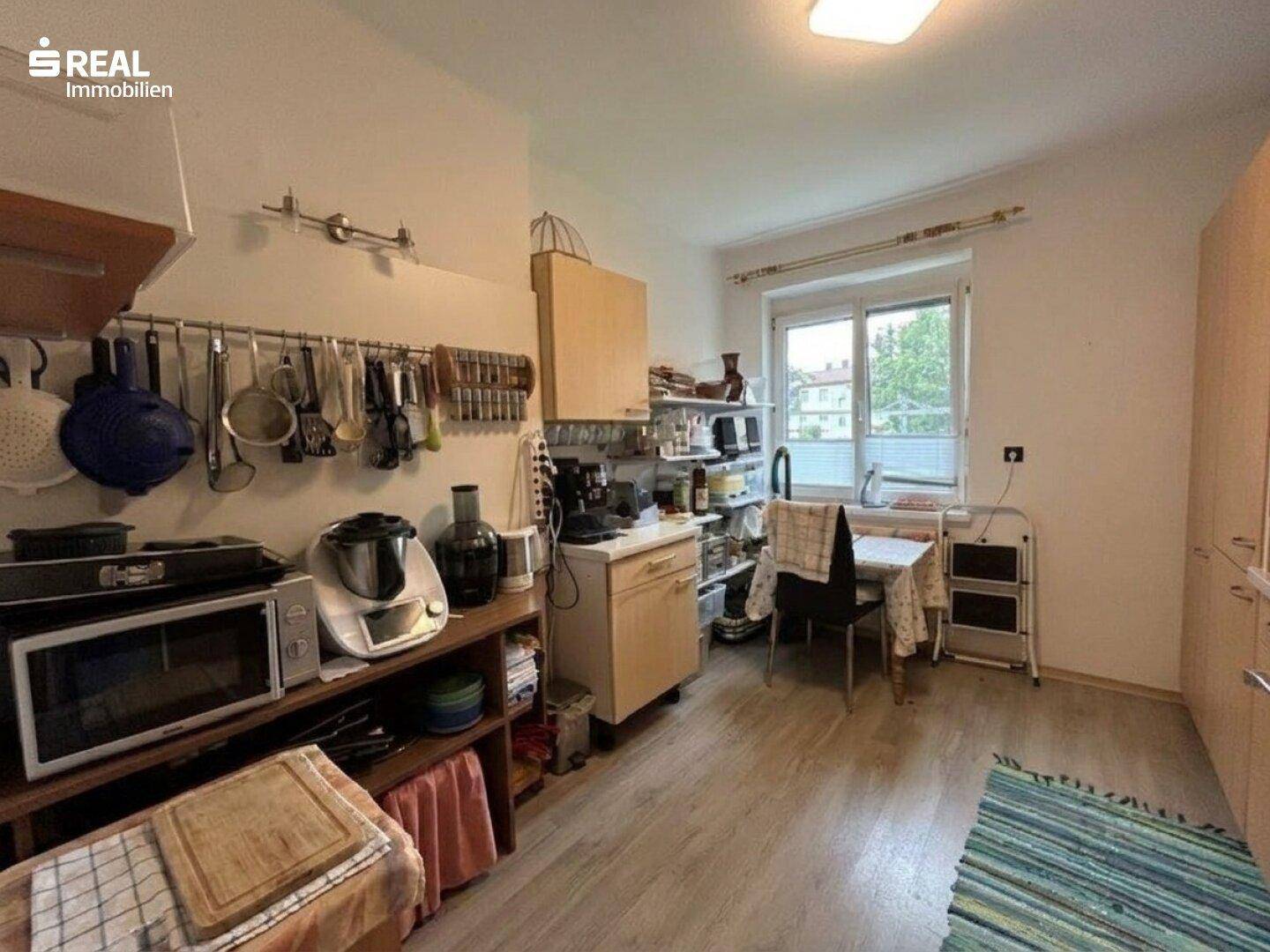 Gemütliche Wohnküche mit Esstisch am Fenster und viel Stauraum.