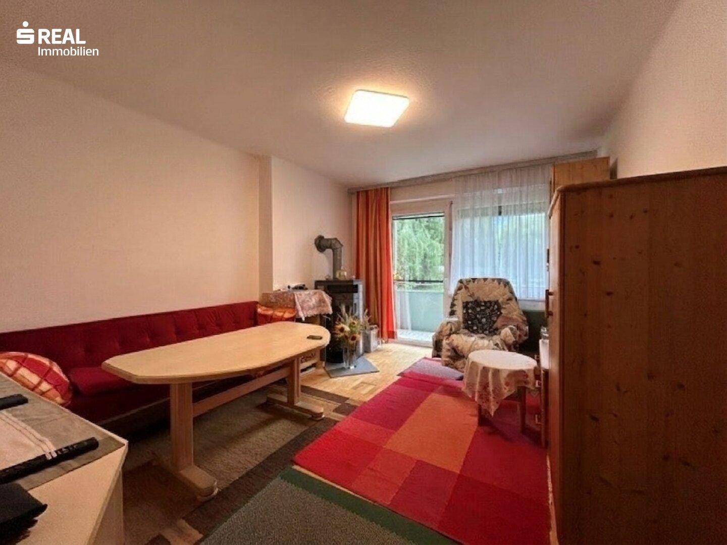 Wohnzimmer mit Holzofen, Essbereich und Zugang zum Balkon.