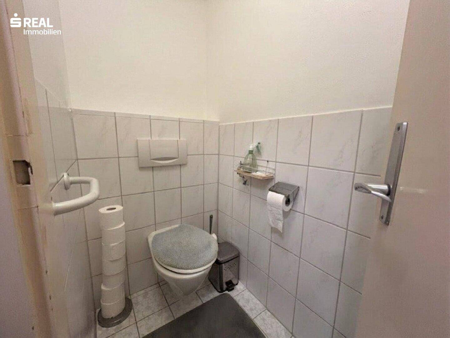 Separates WC mit Wandfliesen und Toilette.