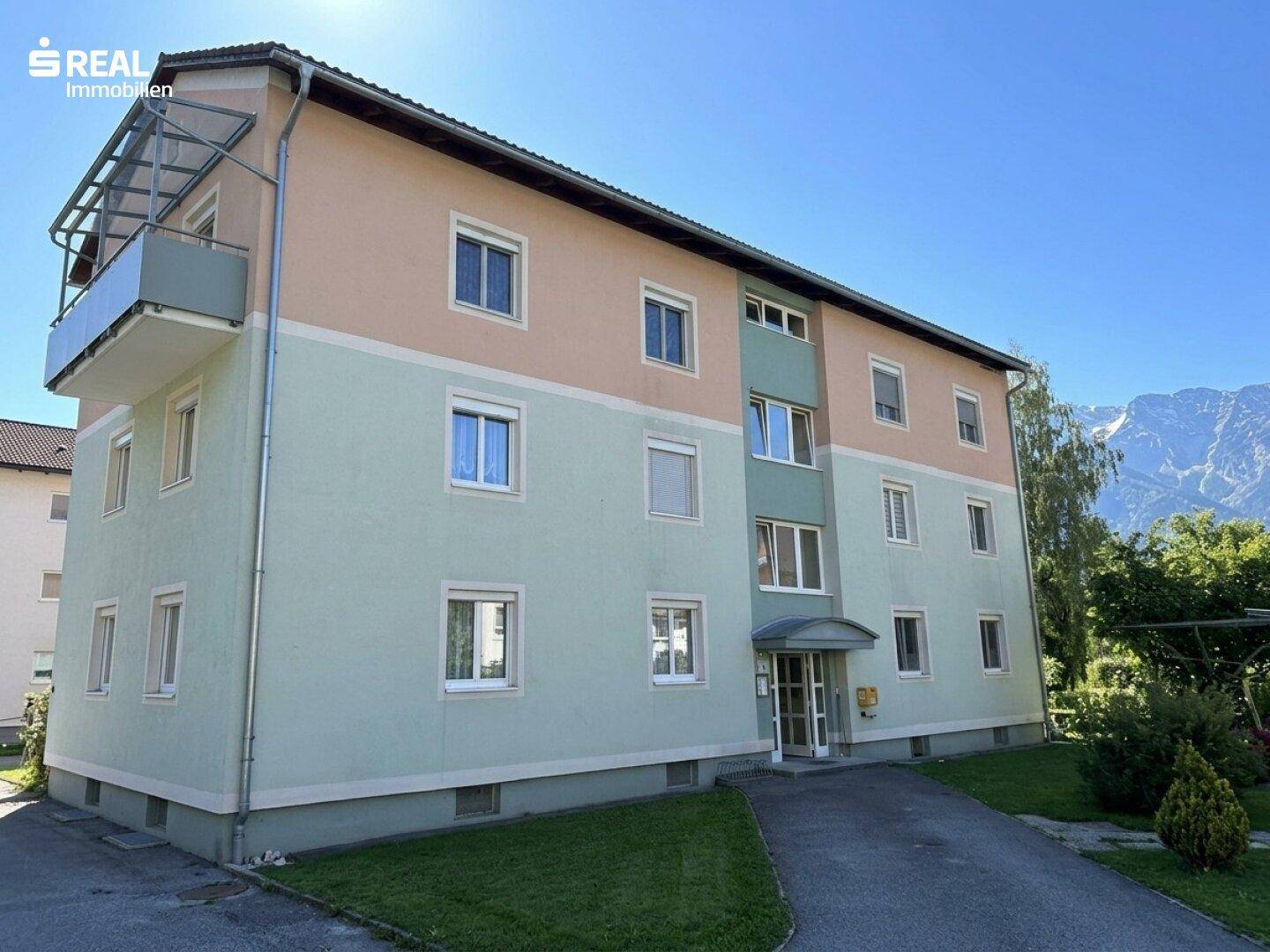 Mehrfamilienhaus mit farbiger Fassade und Balkonen in sonniger Lage.