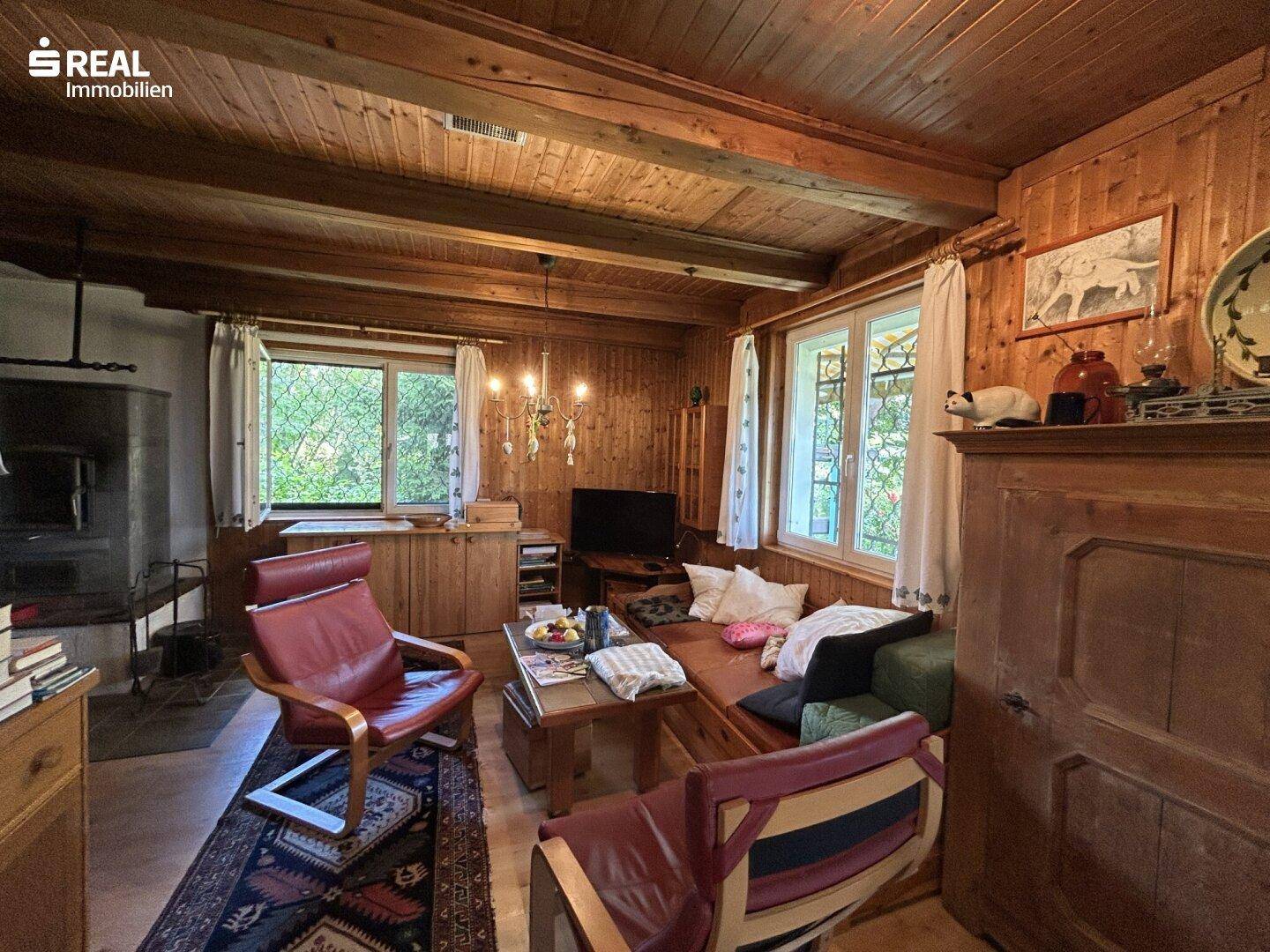 Gemütliches Wohnzimmer im alpinen Stil mit Holzbalkendecke, Kamin und traditionellen Möbeln.