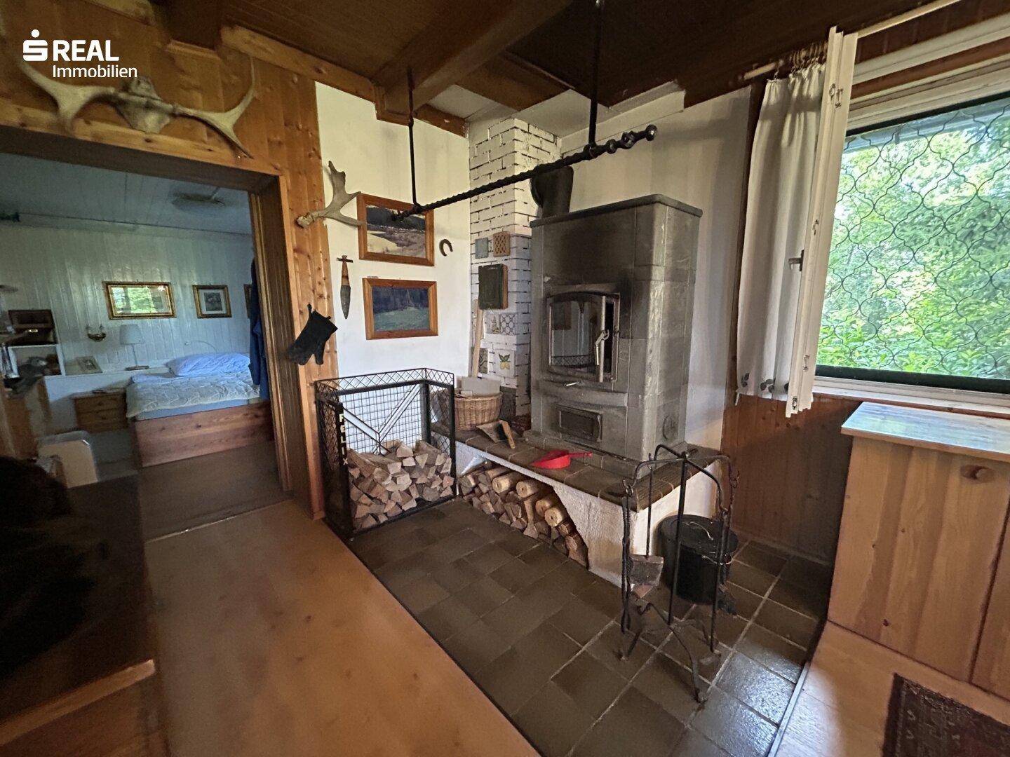Flur mit traditionellem Kachelofen, Holzverkleidung und Zugang zu einem Schlafzimmer.