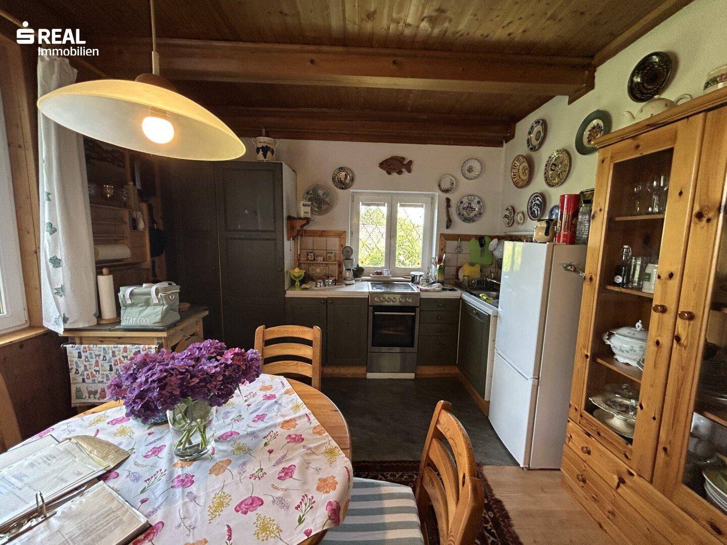 Rustikale Wohnküche mit Holztisch, traditionellen Schränken und Blick auf den Garten.