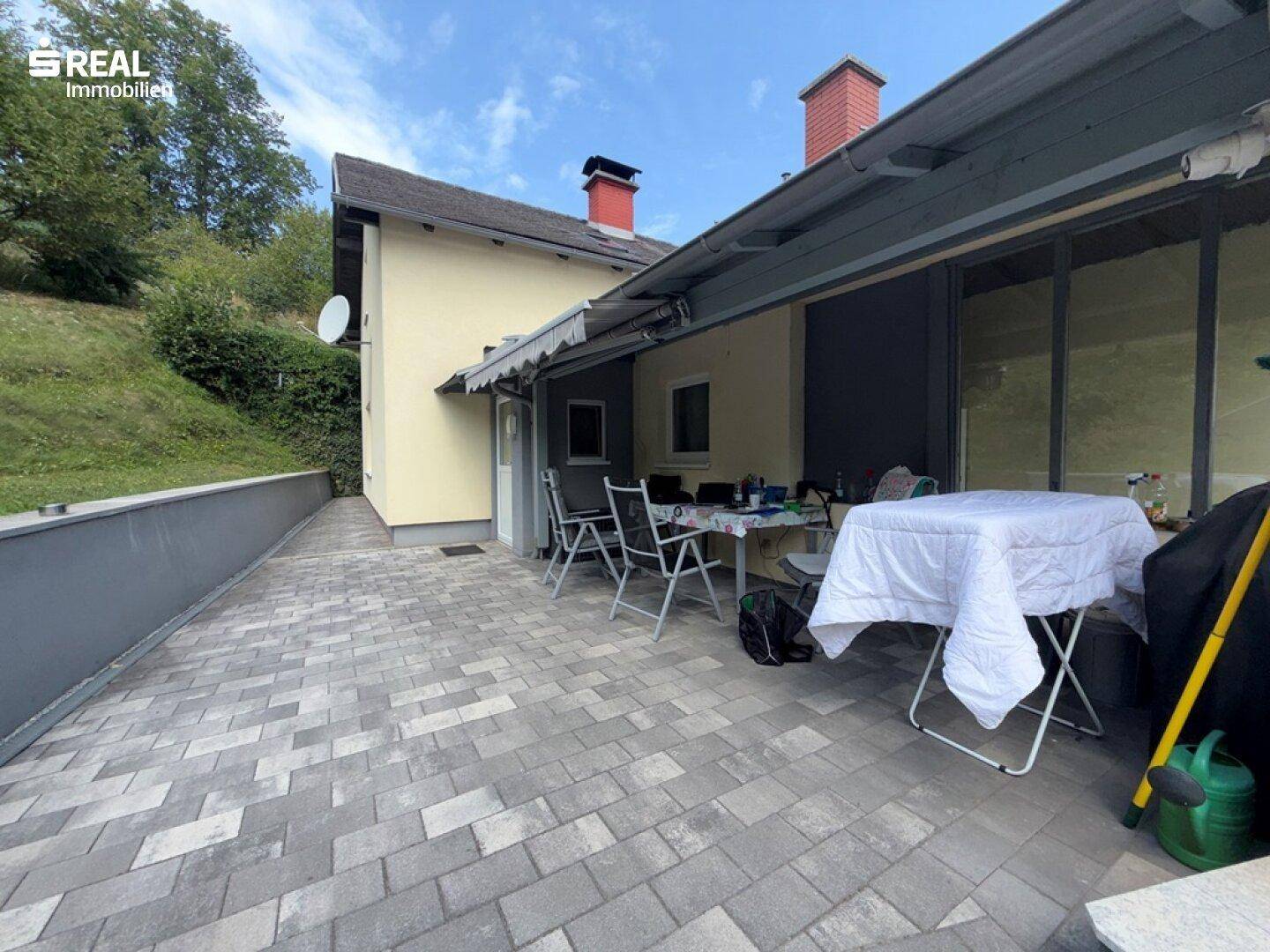 Geräumige, gepflasterte Terrasse mit Sitzgelegenheiten und Markise, ideal für entspannte Stunden im Freien.