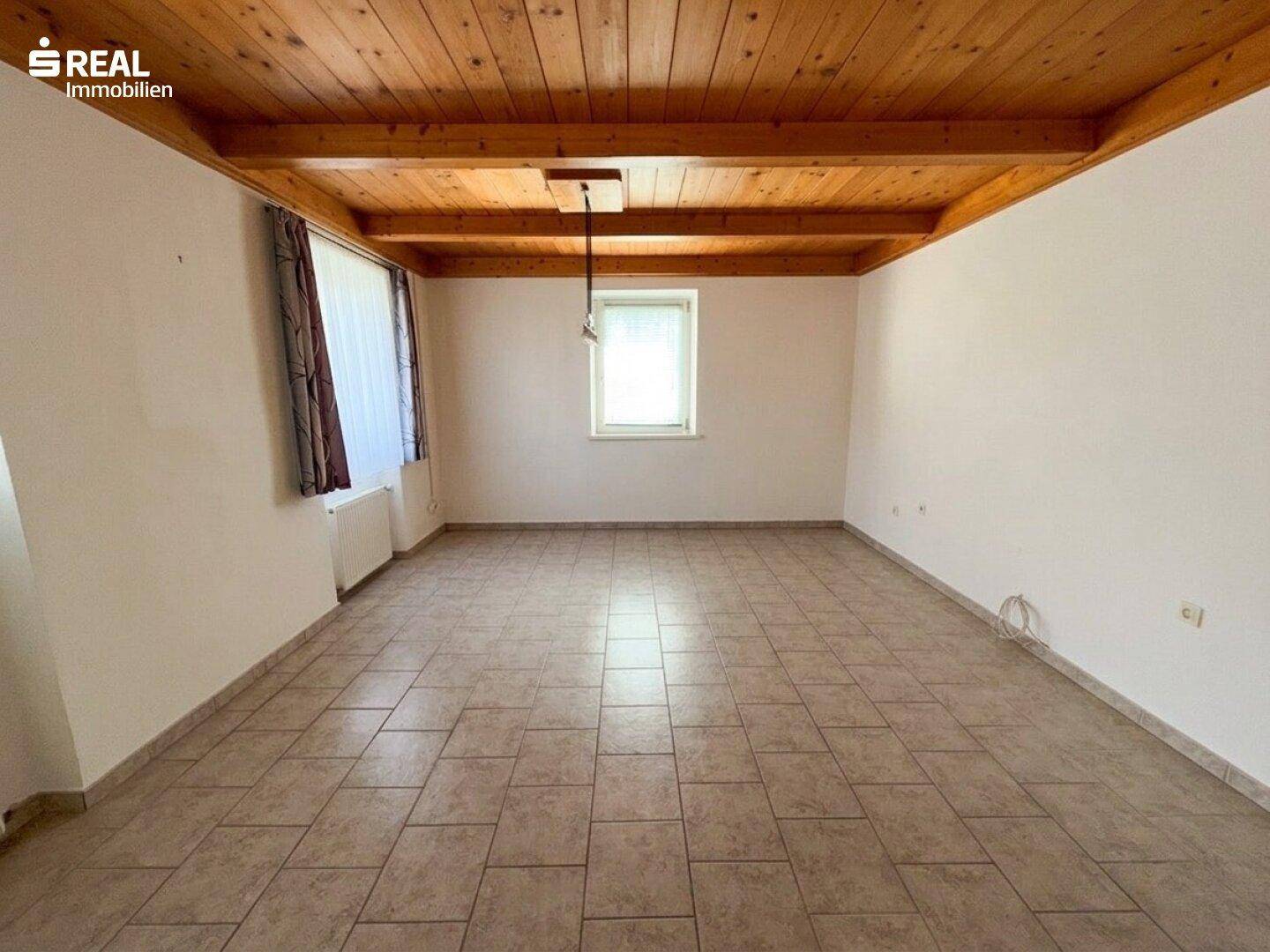 Heller Raum mit Holzdecke und Fliesenboden, bietet viel Platz für individuelle Gestaltung.