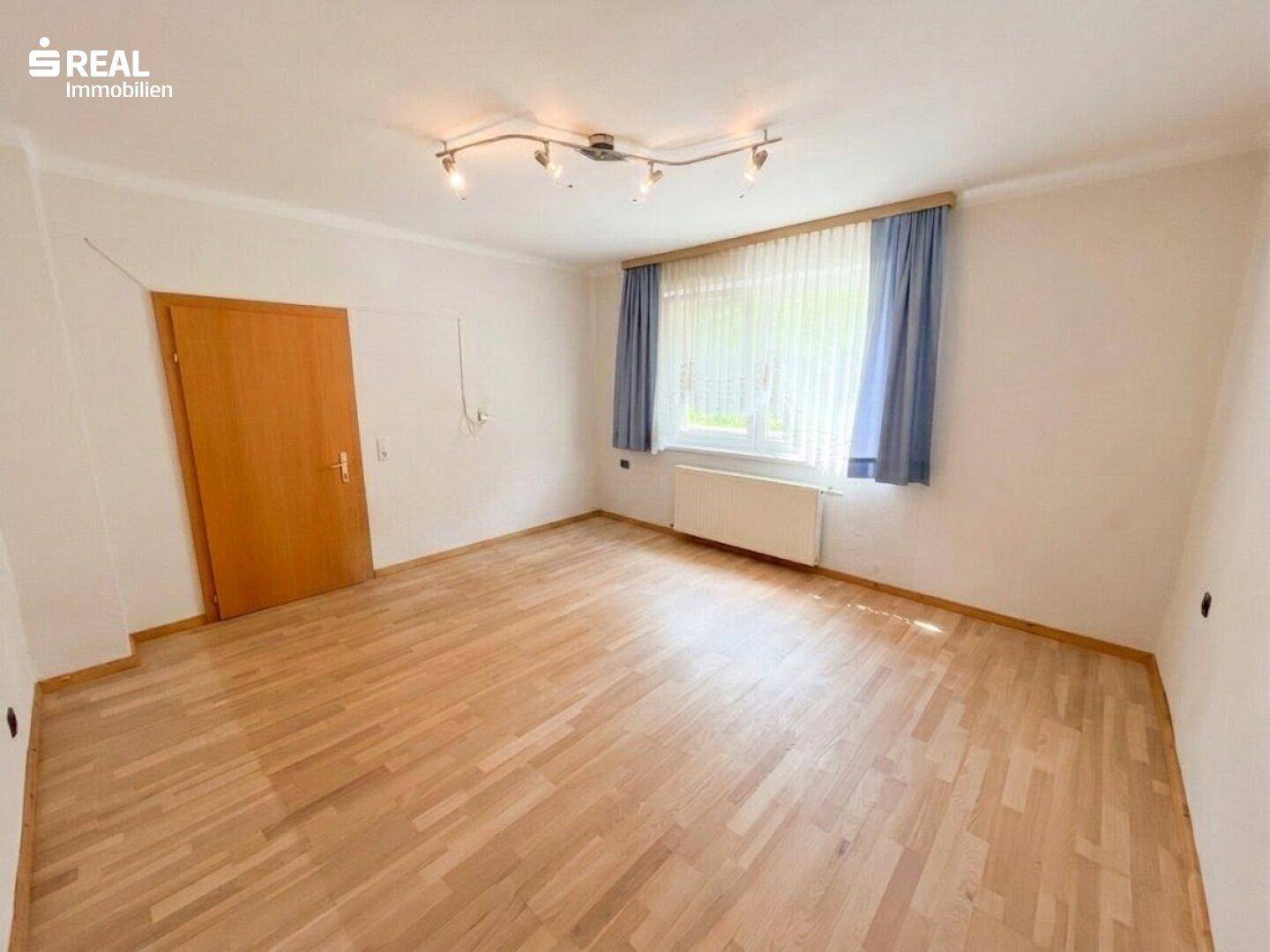 Geräumiges Schlafzimmer mit Holzboden und Fenster, das viel Tageslicht hereinlässt.