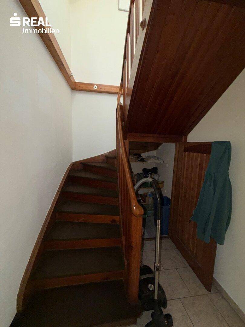 Rustikale Holztreppe führt in die obere Etage, mit praktischem Stauraum darunter.