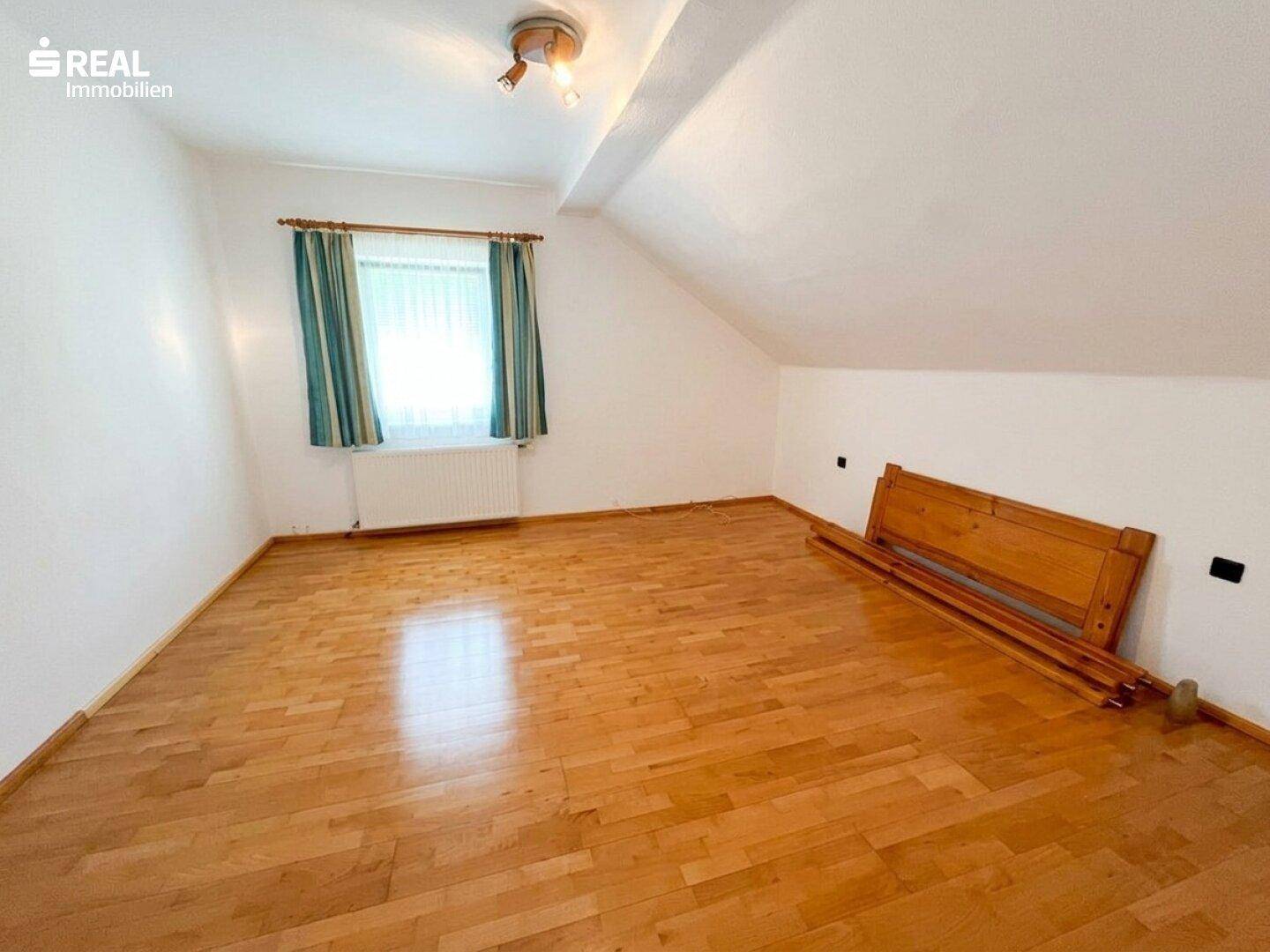 Helles Schlafzimmer im Dachgeschoss mit Holzfußboden, Fenster und viel Platz für individuelle Gestaltung.