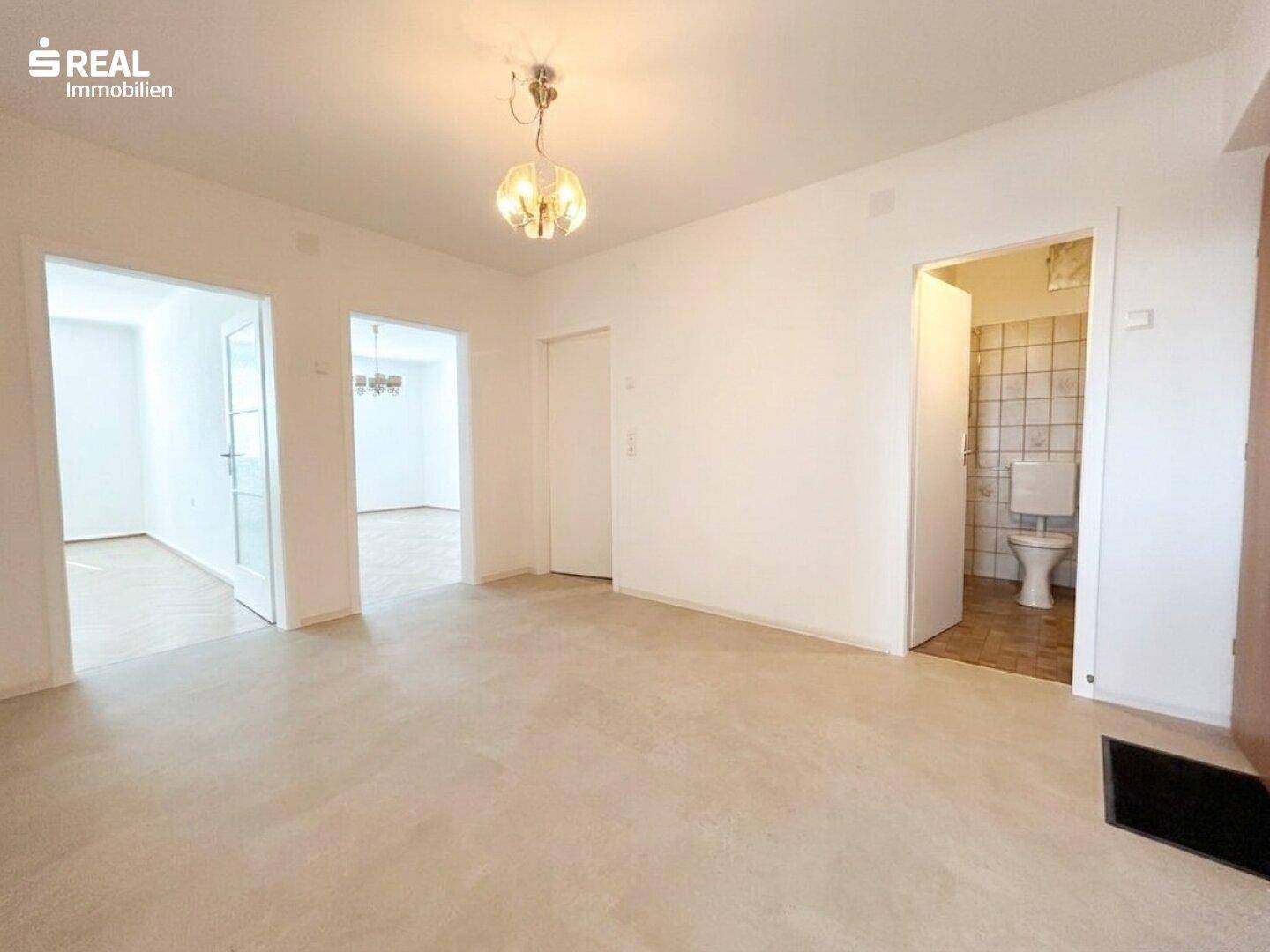 Geräumiger Flur mit hellem Bodenbelag und Zugang zu verschiedenen Räumen, inklusive einer separaten Toilette.